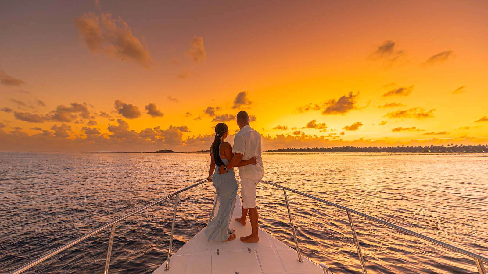 A couple gazing to the sunset on a boat and the Ocean at Nala maldives adults only resort