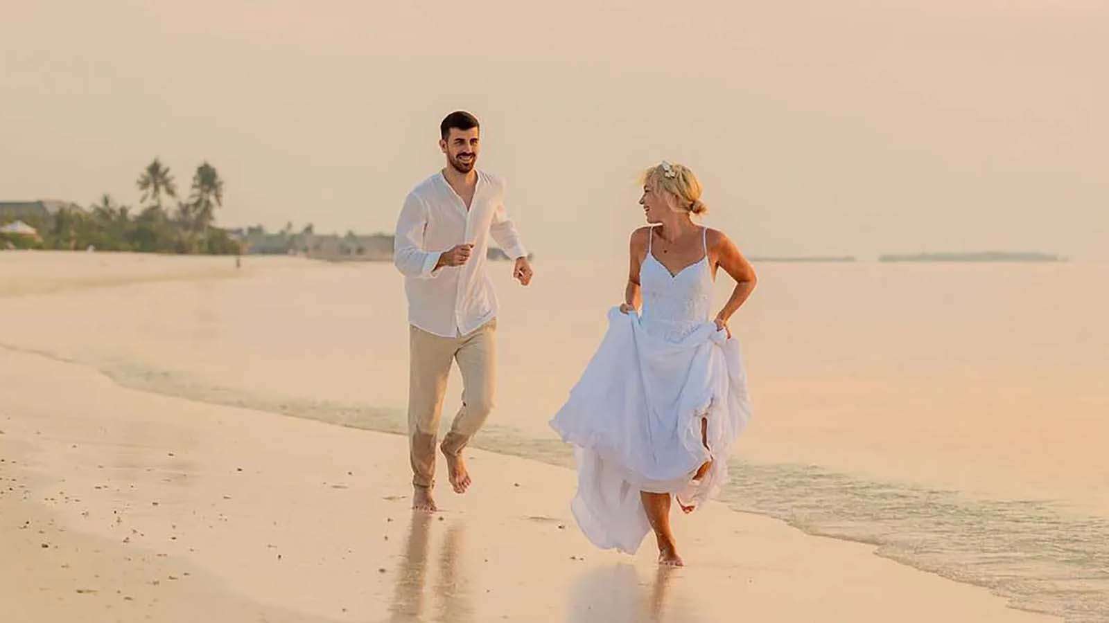 A couple running on the beach at jawakara in the maldives for a vow renewal