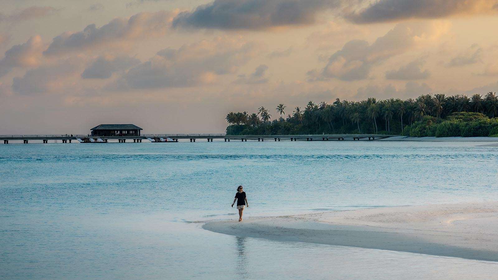 A woman on a beach in the shoreline Nala Maldives Island resort
